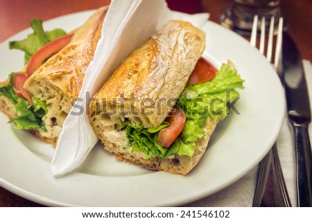 Table set with a sandwich with cheese, lettuce and tomato