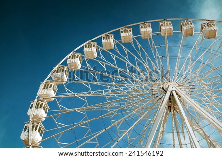 White ferris wheel in a fair and amusement park under blue sky