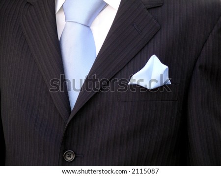 Groom\'s torso with blue tie, blue handkerchief and black suit.
