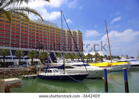 Luxurious yachts docked in marina near large hotel