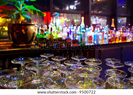 Glasses and assorted colorful bottles of alcoholic drinks in a night-club