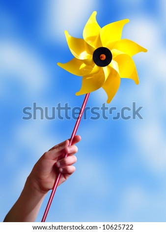 Children\'s hand holding a yellow toy windmill.