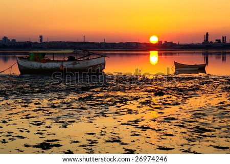 Low tide in a fishing river beach with boats at sunset