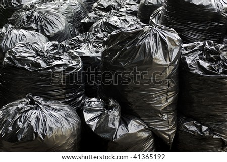 A pile of black garbage plastic bags with tons of trash