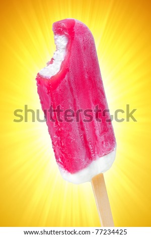 Closeup of a bitten frozen strawberry popsicle over a yellow sparkling background