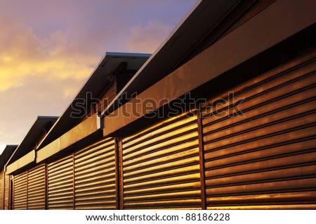 Row of closed storage cabins with stripped wooden walls under warm sunset light
