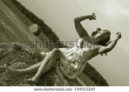 Young woman having fun on the field with hay bale rolls