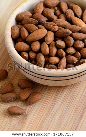 Raw peeled almond nuts in a woodel bowl