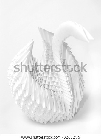 White paper origami swan on white background, shallow DoF with focus on center of swan\'s body.