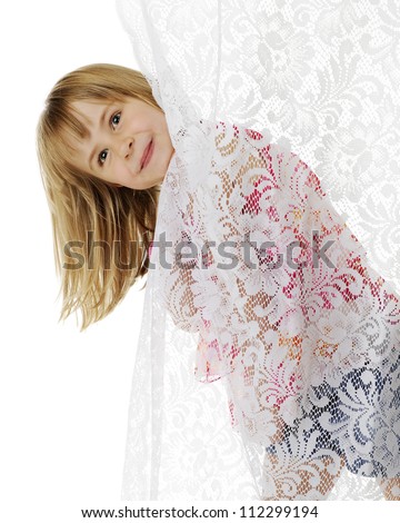 A cute elementary girl peeking her head out from behind a lace curtain.  On a white background.