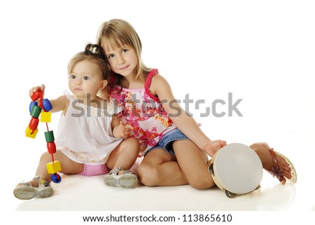 Young sisters playing together.  The older one stops for a moment to pose with the baby.  On a white background.