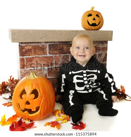 An adorable baby happily sitting among pumpkins and fall foliage in his skeleton costume.  On a white background.
