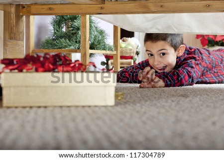 A young elementary boy delighted at seeing a boxed gift under his parents\' bed.