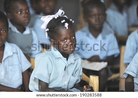KOLMINY HAITI - FEBRUARY 12, 2014:    A young Haitian school crying girl in her classroom, surrounded by her classmates.  Shallow depth of field with focus on  tearful girl.