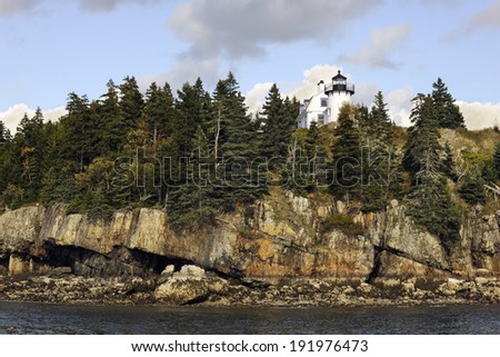 A Bar Harbor, Maine lighthouse up on a rocky cliff, taken from the water level.  Focus on the lighthouse.