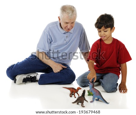 An adorable preschooler showing his grandpa his collection of toy dinosaurs.  On a white background.