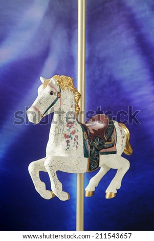 A white, antiqued carousel horse against a lighted blue/purple background.
