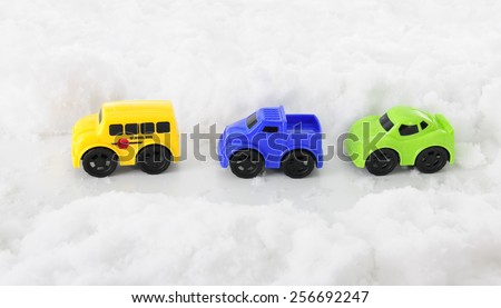 High view of three toy vehicles traveling along a pass through deep snow.