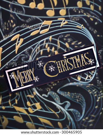 A Merry Christmas sign wrapped in pale blue staff with golden notes.  On a black background.