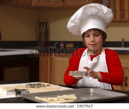 Cute Girl in Chef's Hat and Apron Putting Christmas Cookie Cutouts onto Baking Pan