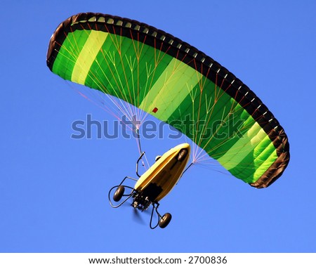Paraglider against a solid blue sky.