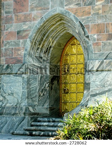 A beautifully sculpted golden door set in a marble building.