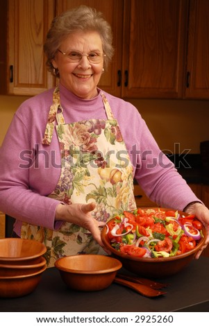 Happy grandma displaying her tossed salad.  Focus on senior woman.