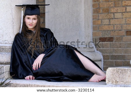 Barefoot middle school graduate resting by the pillars of her school
