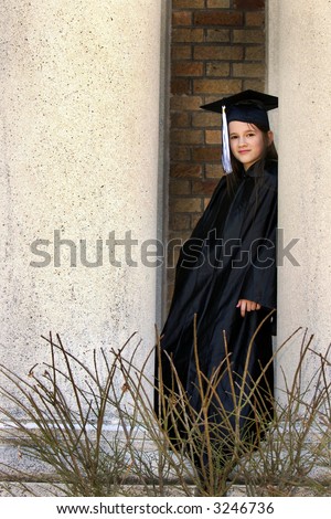 Middle school graduate  in cap and gown leaning between the pillars of her school.