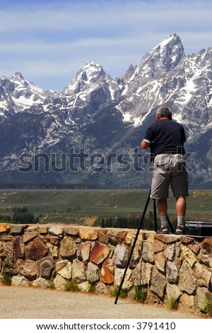 Photographer standing on a ledge to get his shot of a valley below.