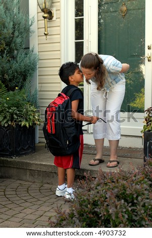 Mother on her front steps kissing her young elementary son good-bye as he heads off for school.