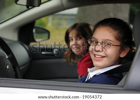 stock photo A happy preteen girl behind the wheel of a car her younger