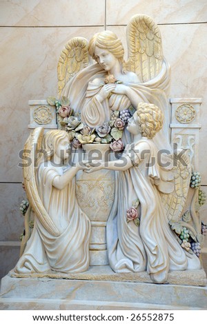 A white statue of one adult angel and two \
