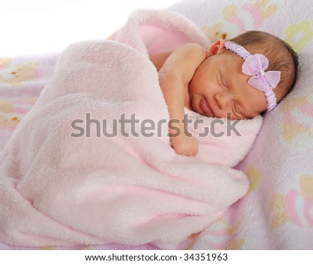 A beautiful newborn wearing only a hair bow and bundled only in a soft, pink blanket.