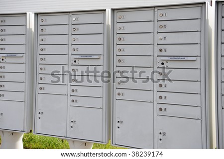 Stacks of multiple locked mail receptacles with slots for depositing mail, all located outside.