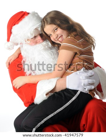 stock photo A young preteen laughing while giving Santa a hug on his lap