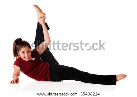 A reclining happy preteen lifting one leg far over her head.  Isolated on white.