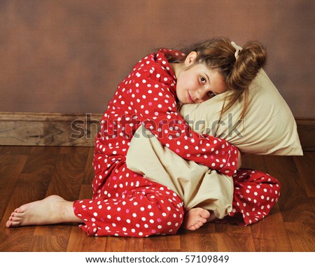 stock photo A young preteen in polkadot pajamas hugging her pillow