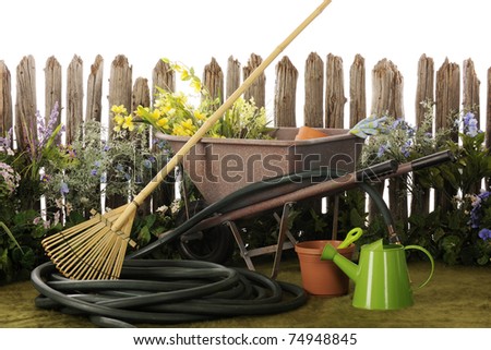 Flowers and garden tools by a weather, old picket fence.