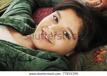 A happy young teen relaxed on multiple throw pillows.
