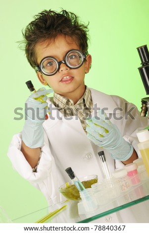 An adorable preschooler in coke-bottles glasses, lab coat and gloves, handling gooey slime and a test tube.