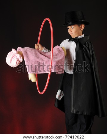 A young magician running a hoop over a doll to prove there\'s nothing holding the doll e\'s levitating.