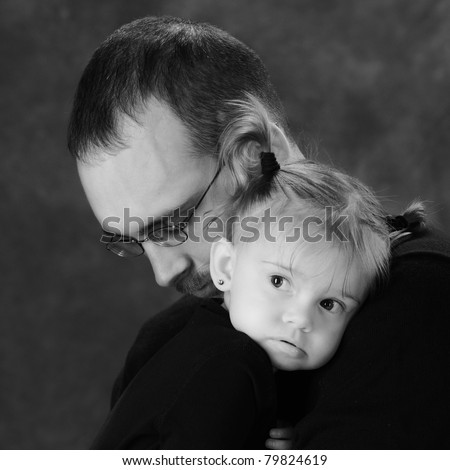 A black and white portrait of a shy baby girl clinging to her comforting dad.