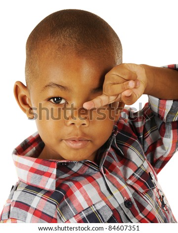 An adorable preschooler rubbing his eyes while pointing with his finger.  On a white background.