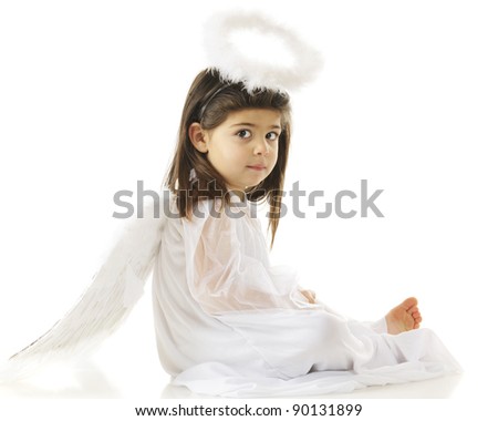 A beautiful preschooler sitting pretty in her angel gown, wings and halo.  On a white background.