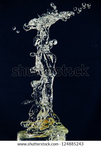 high splash and spray water from falling into a glass of lemon, a photo on a blue background.