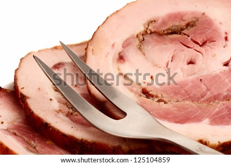 smoked meat, cut into slices and fork are on the plate.