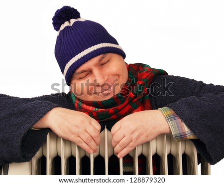 warmly dressed man warms himself at home oil radiator.