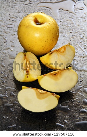 whole apple and four sliced ??on a dark glass with water drops.
