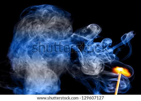 fire lighted match and colored smoke isolated on a black background.